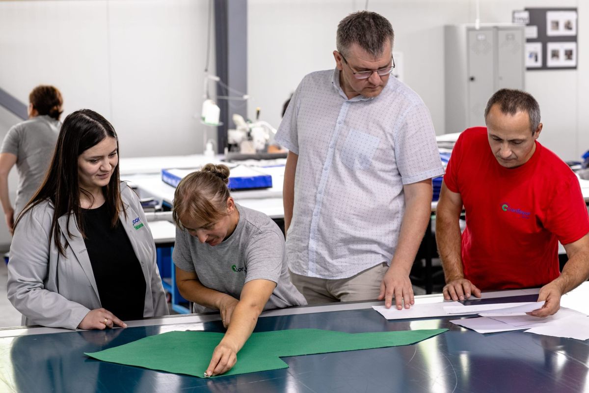 4 people inspecting and cutting out a piece of textile