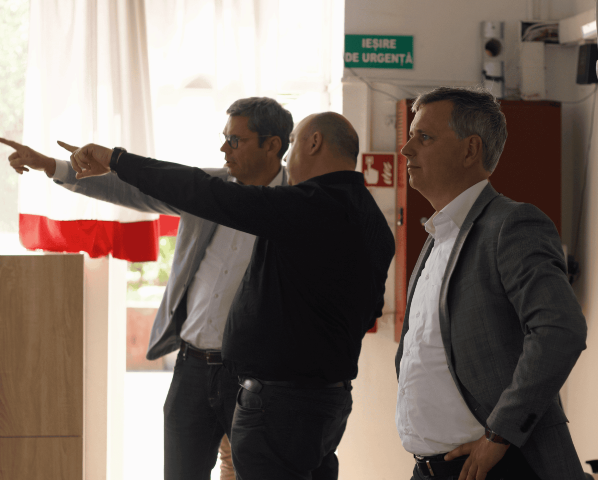 A person staring into the distance. In the back of the picture are two men talking to eachother and pointing to the distance.