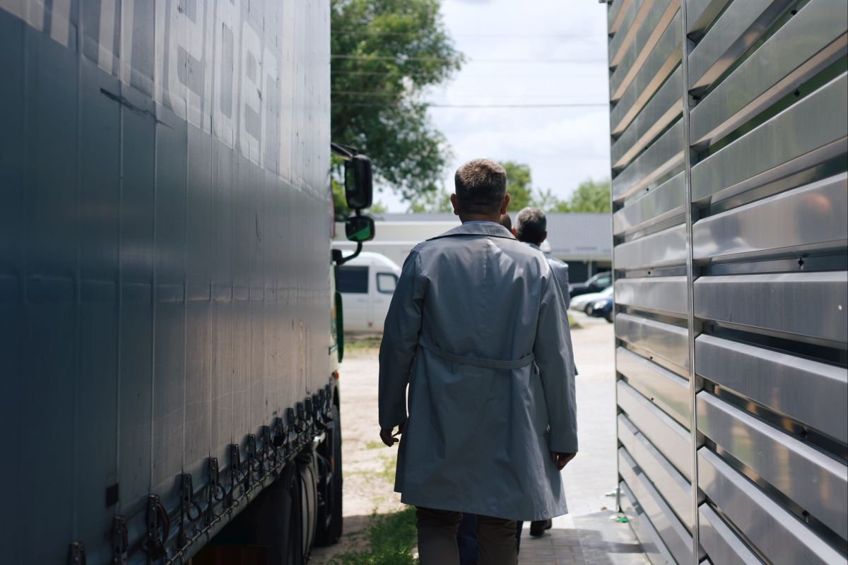 A man walking away from the camera in betwee two trucks