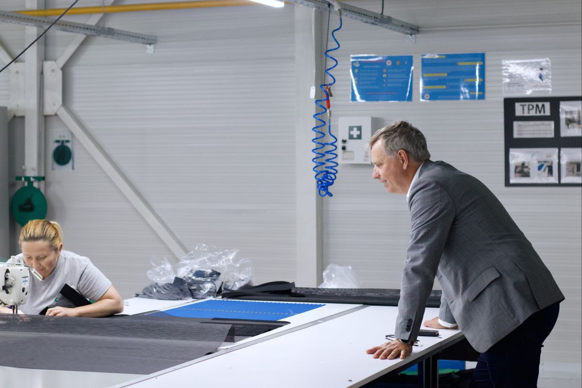 A man watching a woman cut textile in the conTeyor development center